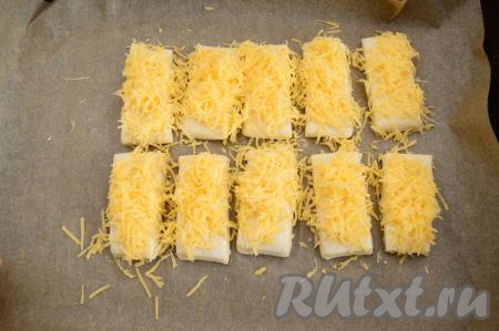 Равномерно разложить натёртый сыр по заготовкам слоёных язычков. 