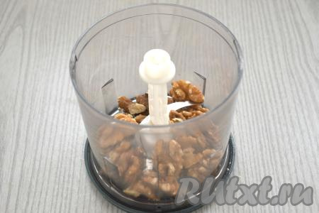 Очищенные орехи (у меня - грецкие) можно немного подсушить, для этого их нужно выложить на сухую разогретую сковороду и на среднем огне, помешивая, обжарить в течение 3-5 минут. Затем убрать с огня, дать остыть. Орехи перекладываем в чашу измельчителя, измельчаем до получения крошки. Если нет измельчителя, можно порубить орехи ножом до получения крошки.