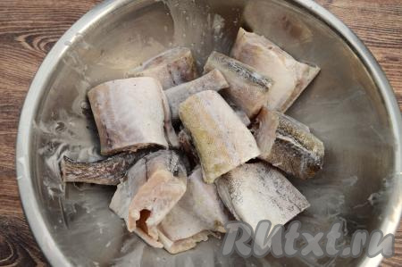 Сложить кусочки минтая в миску, посолить, добавить специи для рыбы и 2 столовых ложки сметаны. Тщательно перемешать, равномерно покрывая рыбку со всех сторон сметаной и специями.