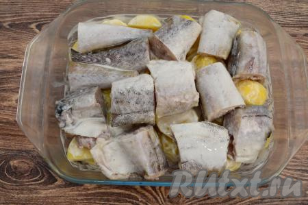 Поверх картошки разложить кусочки минтая. Отправить форму в разогретую до 180 градусов духовку на 30 минут. Затем минтая сверху смазать отложенной сметаной и отправить рыбу с картофелем запекаться в духовку ещё на 20 минут.