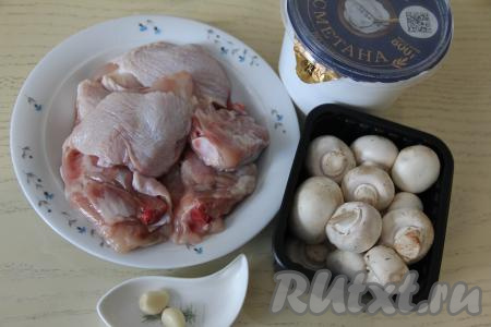 Подготовить продукты для приготовления куриных бёдер с грибами в сметанном соусе на сковороде. Чеснок почистить. Куриные бёдра промыть водой, обсушить. Для этого блюда можно взять как шампиньоны (свежие или замороженные), так и предварительно отваренные в течение 25-30 минут лесные грибы. Замороженные грибы размораживать не нужно. Свежие шампиньоны нужно будет промыть водой, убирая с них все загрязнения.