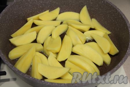 В сковороду влить растительное масло, хорошо его разогреть на сильном огне. Выложить обсушенную картошку. Сделать огонь средним.