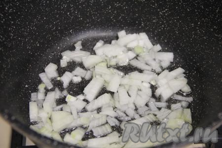 В глубокой сковороде (или в кастрюле с толстым дном) разогреть растительное масло, выложить мелко нарезанный лук. Периодически перемешивая, на среднем огне обжарить лук до прозрачности (в течение 4-5 минут), иногда помешивая.