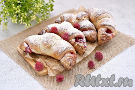 Достаём готовую выпечку из духовки, даём остыть. А затем воздушные круассаны, приятно похрустывающие снаружи и с сочной малиной внутри, по желанию, посыпаем сахарной пудрой и подаём к чаю.