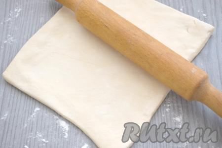 Присыпаем стол мукой, затем выкладываем размороженное слоёное тесто и раскатываем его скалкой в прямоугольник толщиной примерно 3 миллиметра.