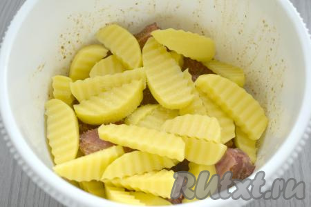 Картофель очищаем, нарезаем на ломтики средней толщины, немного солим, перемешиваем, добавляем к замаринованным свиным рёбрышкам.