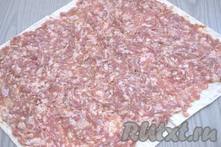 Расстилаем на столе тонкий лист лаваша. У меня лаваш размером 35 сантиметров на 29 сантиметров. Выкладываем на лист лаваша фарш и, оставляя по 1 сантиметру от краёв лаваша чистыми, равномерно распределяем фарш по лавашу.