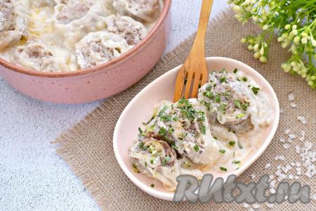 Достаём форму с готовым блюдом из духовки. Сочные, вкусные, нежные ленивые пельмени из лаваша вместе со сметанным соусом раскладываем по тарелкам и в горячем виде подаём к столу, посыпав, по желанию, зеленью.