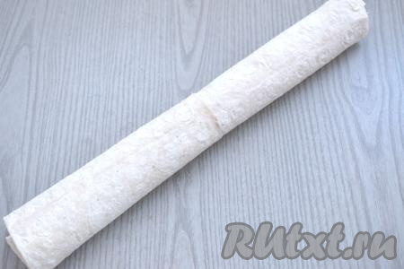 Начиная с длинной стороны, сворачиваем лаваш с фаршем в плотный рулет.