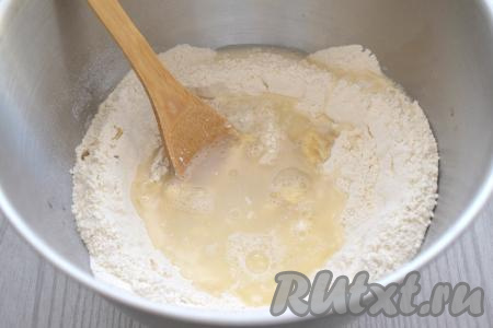 В чайнике доводим до кипения 300 миллилитров воды. Начинаем небольшими порциями в центр мучной смеси аккуратно вливать кипяток. После добавления каждой порции кипятка тщательно перемешиваем, замешивая пельменное тесто. Вначале перемешиваем тесто ложкой. Делайте замес очень аккуратно, ведь кипятком можно обжечься.