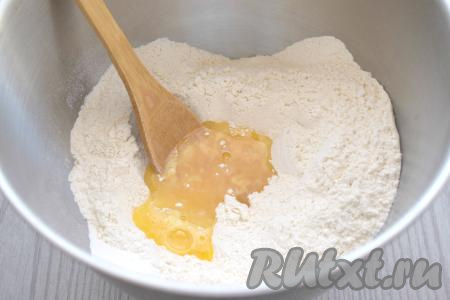 В просеянной муке делаем небольшое углубление, вливаем в него яичную смесь и растительное масло, немного перемешиваем.