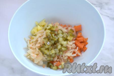 Если квашеная капуста очень кислая, её желательно выложить в дуршлаг, промыть холодной водой, отжать от лишней воды. В миску с картошкой и морковью выкладываем квашеную капусту и солёные огурцы, нарезанные на небольшие кубики. 