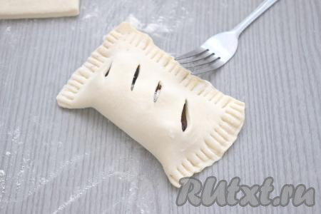 Сторону с ежевикой накрываем стороной теста с надрезами. Тщательно скрепляем края теста с помощью вилки. Если вилка будет сильно липнуть к тесту в процессе скрепления краёв, тогда периодически обмакивайте зубцы вилки в муку. 