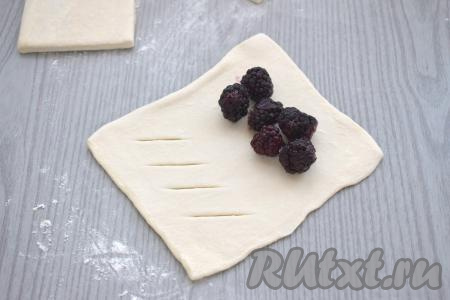 На часть теста без надрезов, отступив от краёв 1-1,5 сантиметра, выкладываем несколько ягод ежевики.