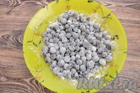 После того как бисквитное тесто будет замешано, нужно в тарелку всыпать подготовленную чёрную смородину, добавить 10 грамм муки, тщательно перемешать, покрывая ягоды мукой со всех сторон. Смородина, обваленная в муке, будет лучше распределяться по бисквитному тесту.