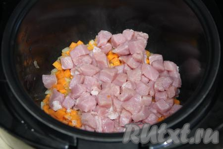 К обжаренным овощам выложить свинину, нарезанную на кубики с размером стороны 1,5 сантиметра, перемешать.