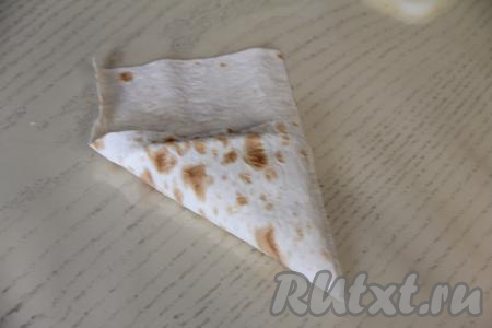 Постепенно, заворачивая лаваш с начинкой в виде треугольника, сформировать пирожок. Оставшийся кусочек лаваша загнуть внутрь получившегося пирожка.