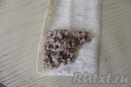 Мясную начинку тоже разделить на 8 равных частей. Выложить одну часть начинки на край полоски из лаваша, отступая от краёв лаваша, как на фото.