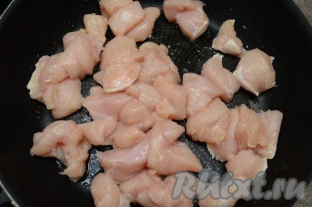 Куриное филе нарезать на кубики с размером стороны 2-3 сантиметра. Посолить мясо по вкусу, перемешать. В сковороде разогреть растительное масло, выложить нарезанное куриное филе.