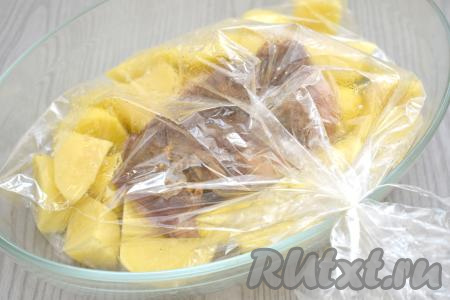 Добавляем к картофелю замаринованную утиную грудку. Завязываем концы рукава с двух сторон. На поверхности рукава делаем ножом 4-5 проколов для выхода пара.