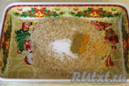 В жаропрочную форму (я взяла форму размером 25 сантиметров на 16 сантиметров) выложить рис, добавить соль и специи по вкусу. Специи можно взять любые, но я обычно в это блюдо добавлю, помимо остальных специй, щепотку куркумы, она делает рис более ярким и ароматным.