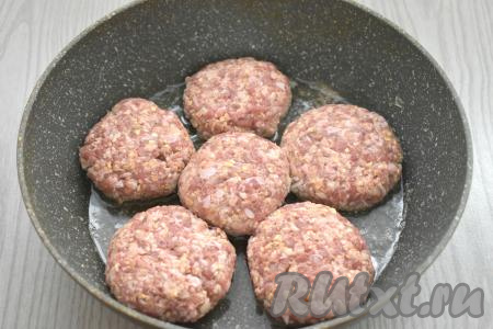 Из получившейся мясной основы лепим 6 котлет. Разогреваем в сковороде растительное масло. Выкладываем в горячее масло заготовки котлет. Обжариваем котлеты из свинины с овсяными хлопьями на среднем огне по 6-7 минут с каждой стороны.