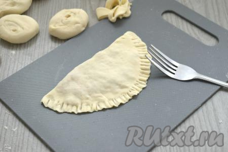 Накрываем начинку свободной стороной лепёшки. Плотно прижимаем края и фиксируем их вилкой. Если вилка прилипает к тесту, тогда периодически окунайте кончики вилки в муку. Аналогично формируем все заготовки чебуреков.