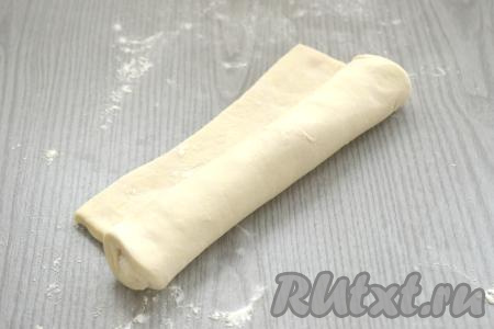 На присыпанной мукой поверхности пласт размороженного слоёного теста, не раскатывая, сворачиваем в плотный рулет.