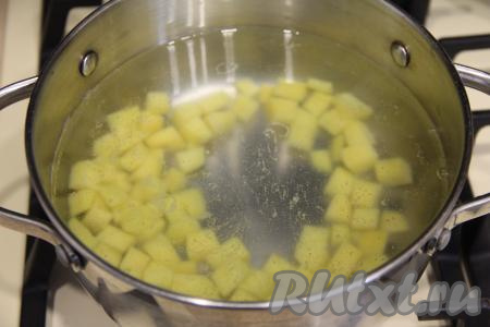 В кастрюлю влить 2 литра воды, сразу поставить на огонь. Картошку почистить, нарезать на средние кубики. В кастрюлю с закипевшей водой выложить картошку, дать закипеть, варить 5 минут на небольшом огне.&nbsp;