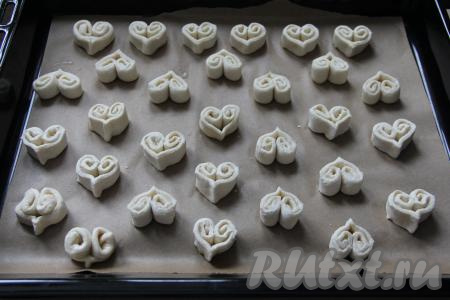 Противень застелить пергаментом, выложить получившиеся рулетики на противень, придавая им форму сердечек.&nbsp;Аналогично подготовить заготовки печенья из второго пласта теста и тоже выложить на противень. Выкладывать "сердечки" нужно на небольшом расстоянии друг от друга.