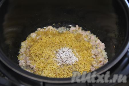 Всыпать соль, чёрный молотый перец по вкусу, перемешать, обжарить булгур с фаршем в течение 2-3 минут, помешивая.