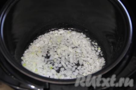 В чашу мультиварки влить растительное масло, установить на 15 минут режим "Жарка". Лук мелко нарезать, выложить его в чашу мультиварки и обжарить до прозрачности (ориентировочно в течение 5 минут), не забывая периодически помешивать.
