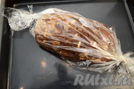 По прошествии 2 часов свиной карбонат достать из холодильника. Присолить верхнюю часть куска мяса 1 чайной ложкой соли и немного её втереть в мясо. Выложить целый кусок мяса в рукав для запекания, туда же влить остатки соевого соуса, в котором мариновалось мясо. Завязать концы рукава с двух сторон. Поместить рукав на противень и отправить свинину запекаться в разогретую до 200 градусов духовку на 1 час 10 минут.