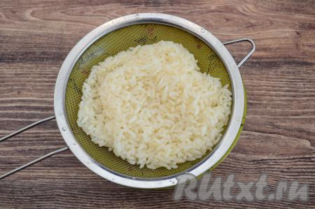 В кастрюлю, в которой будете варить рис, влить миллилитров 300 воды, поставить на огонь. Пока вода в кастрюле закипает, насыпать в сито рис, хорошо промыть под проточной водой. В кастрюлю с закипевшей водой выложить подготовленный рис, перемешать, снова дать воде закипеть, уменьшить огонь. Отварить рис до готовности (на варку обычно требуется минут 20, рисинки должны стать мягкими). Сварившийся рис откинуть на сито, оставить на несколько минут, чтобы с него стекла лишняя жидкость и он остыл. Поскольку тефтели готовятся без подливы, рис в фарш должен добавляться полностью сваренным. Иначе рис будет вытягивать из тефтелей в процессе приготовления влагу и блюдо получится суховатым, да и некоторые сорта риса просто могут не успеть "дойти" до готовности.