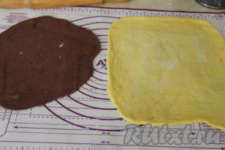 Мы будем формировать два кулича, поэтому разделить апельсиновое и шоколадное тесто на две части (у нас получатся 2 части апельсинового теста и 2 части шоколадного теста). На присыпанной мукой поверхности раскатать скалкой одну часть апельсинового и одну часть шоколадного теста в тонкий пласт. Шоколадный пласт получится чуть меньше, чем апельсиновый пласт.