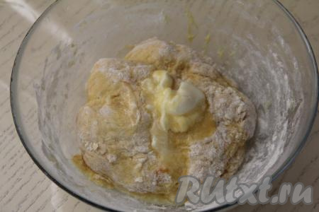 Перемешать тесто столовой ложкой, добавить растопленное не горячее сливочное масло (удобно растапливать масло в микроволновке), перемешать. Затем начать постепенно добавлять оставшуюся муку, тщательно вмешивая её. После того как тесто станет сложно перемешивать ложкой, начинайте вымешивать его руками.