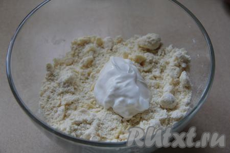 Перетереть массу руками до получения мелкой, однородной крошки. Добавить сметану, перемешать, постепенно собирая тесто в ком. Песочное тесто должно получиться мягким, практически не липнущим к рукам. По мере необходимости понемногу добавить оставшуюся муку, полностью вмешивая её. Как только песочно тесто соберётся в ком и практически не будет липнуть к рукам, значит больше добавлять муку и вымешивать тесто не нужно.