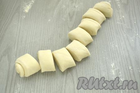 Размороженный пласт слоёного теста на присыпанной мукой поверхности сворачиваем в достаточно плотный рулет (если у вас прямоугольный пласт теста, тогда его нужно сворачивать в рулет, начиная с широкой стороны). Разрезаем рулет из слоёного теста на 8 одинаковых частей.