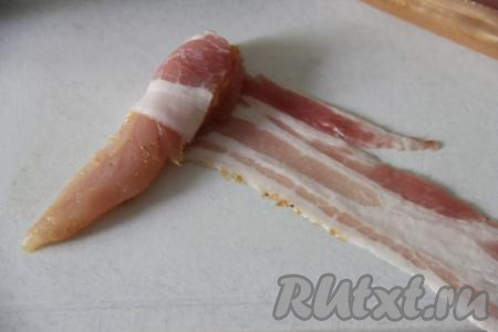 Накрыть миску крышкой, поставить минимум на 1 час в холодильник (можно оставить и на более длительное время), чтобы кусочки куриного мяса промариновались. Затем каждый кусочек куриного филе по спирали обернуть в полоску бекона.&nbsp;