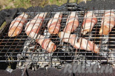 Заранее подготовить угли на мангале. Угли должны быть раскалёнными, но прямого огня быть не должно. Выложить куриное филе в беконе на решётку мангала.