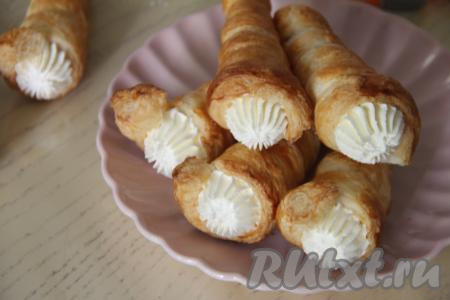 Трубочки из слоёного теста наполнить взбитыми сливками. Если нет кулинарного мешка, можно наполнить трубочки сливками с помощью ложки.