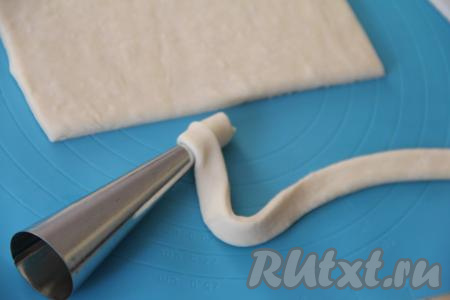 Для формирования трубочек я использовала металлические конусы, купленные в магазине. Конусы, для того чтобы они хорошо отделялись от готовой выпечки, можно немного смазать растительным маслом. Металлические конусы, которые я использую, всегда хорошо отделяются от выпечки, поэтому я маслом их не смазываю. На каждый конус намотать внахлёст полоску из слоёного теста, слегка растягивая тесто в процессе наматывания на конус. Полоску теста нужно наматывать, начиная с узкой части конуса. Когда закончится полоска, хорошо закрепить край теста.