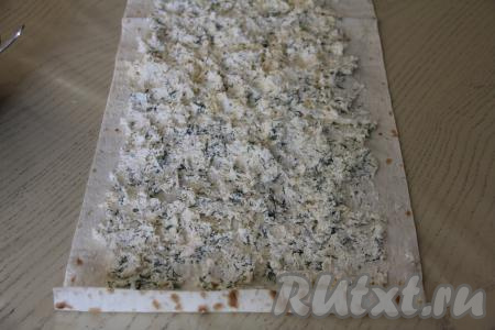 На лист лаваша, отступив от краёв примерно по 1,5 сантиметра, равномерно распределить творожно-сырную начинку.&nbsp;