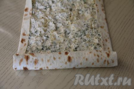 Начиная с более узкой подвёрнутой стороны, свернуть лаваш с начинкой в рулет.&nbsp;