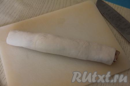 Край теста защипать. Переложить рулет на разделочную доску.