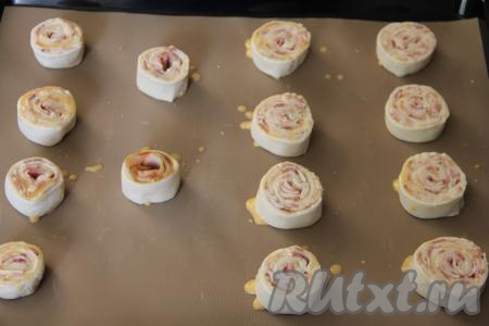 Яичный желток в небольшой ёмкости взбить вилкой в однородную массу. Смазать рулетики взбитым желтком. Поставить противень с рулетиками в разогретую до 220 градусов духовку.