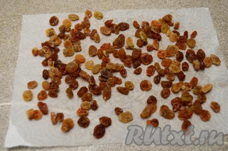 Первым делом изюм поместить в сито, промыть проточной водой. После этого выложить изюм в небольшую ёмкость, залить полностью кипящей водой, оставить на 4-5 минут. Затем откинуть изюм на сито. После того как вода с изюма стечёт, разложить его на бумажном полотенце, дать обсохнуть. Осмотреть изюм, чтобы не было остатков веточек.