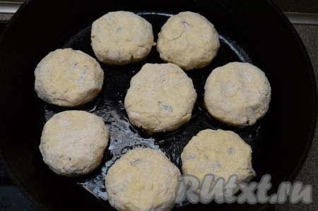 В сковороду влить растительное масло, хорошо его разогреть, затем выложить заготовки сырников с яблоком и изюмом. Жарить их на среднем огне минуты 3-4 (до подрумянивания снизу).