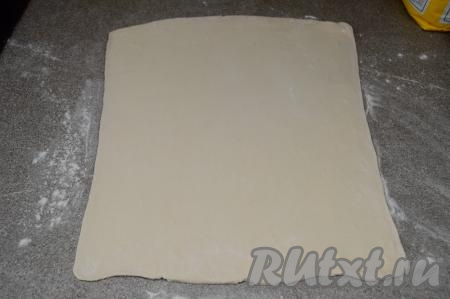 На слегка присыпанной мукой поверхности раскатать разморозившееся слоёное тесто в квадрат со стороной 32 сантиметра.