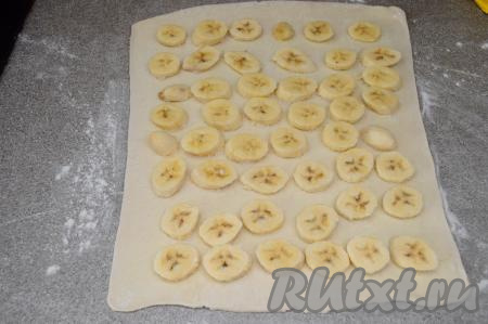 Поверх сахара, отступая от краёв теста по 1 сантиметру, разложить в один слой нарезанные бананы.